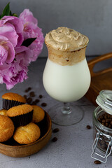 Coffee and milkshake and muffins. Dalgona coffee - the Korean coffee drink on wooden background. Instant coffee or espresso powder whipped with sugar and hot water. Iced coffee and cupcakes.