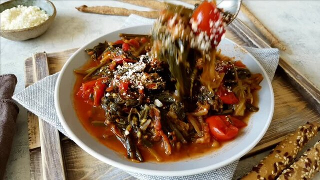 Fork of sauteed green chicory and tomatoes