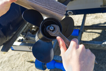 man changing propeller on outboard motor. Repairing outboard motor for boat, replacing screw. © Ilja