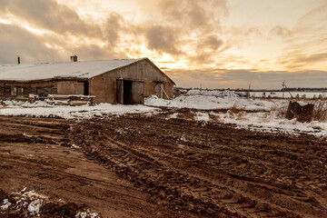 A barn in the middle of a snow-covered winter field next to a broken dirt road © Дэн Едрышов