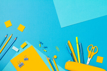 The concept of going back to school. Border frame of yellow and blue pencils, pens, markers on a blue background. Space for text. The view from the top © Fotosova
