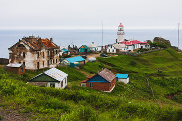Lighthouse, huge rocks on the ocean, sea summer landscape, old stone building on a high cliff,...