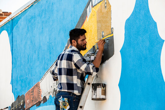 Artists Creating A Train Mural On The Side Of A Building