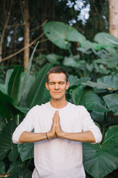 Meditating man with hands together in woods