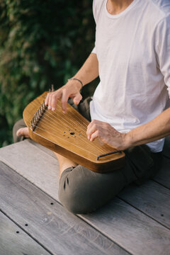 Man playing folk harp on terrace