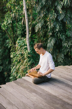 Man playing folk harp on terrace