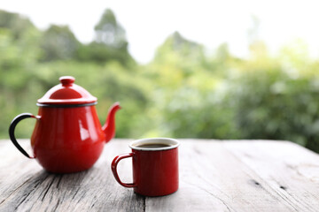 Red coffee cup and red teapot on rustic wooden table