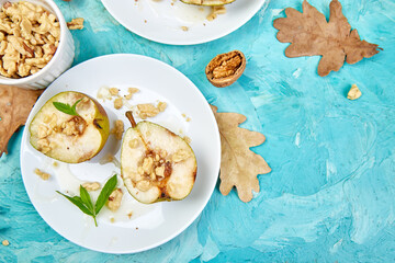 Tasty roast pears with honey and walnuts on blue background table.
