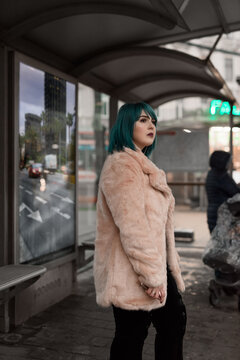 Modern woman in pink fur on bus stop