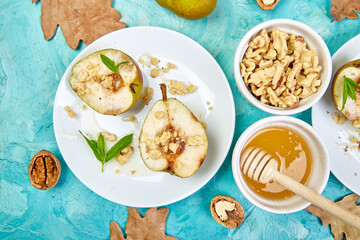 Tasty roast pears with honey and walnuts on blue background table.