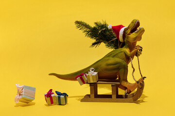 Toy dinosaur sitting on sledge with gifts and fir
