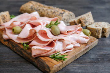 Traditional Italian antipasti mortadella on a wooden plate, served with olives
