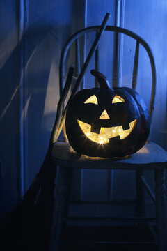 Spooky black pumpkin on chair at night