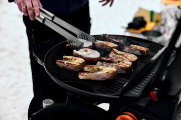 Man grilling delicious fish on a portable BBQ,