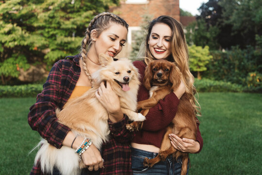 Two female friends in their twenties playing with their dogs outside in autumn