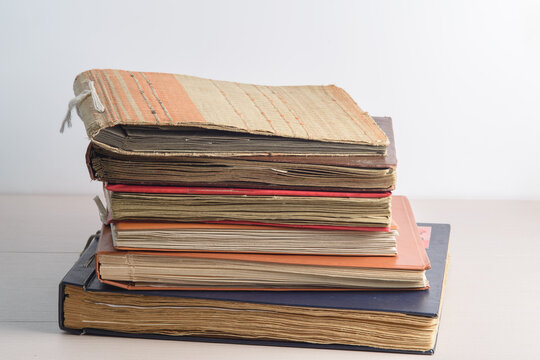 A stack of old faded photo albums or photo books, with yellowed pages on a light background. Copy space, minimal style, the concept of storing memories.
