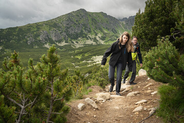 Two people hiking on rocky trail in HIgh Tatras mountains in Slovakia surrounded by dwarf pine and...