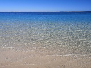 Fototapeta na wymiar Tranquil water's edge on a white sand beach in Australia