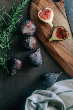 Figs on a dark wooden rustic background sitting at the edge of a table with green thyme.