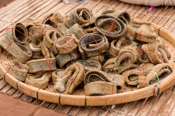 Salt-fermented cow skins cut into bundles together in bamboo racks for burning and cooking.