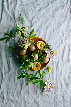 Passionfruit on plate on linen with flowers and foliage