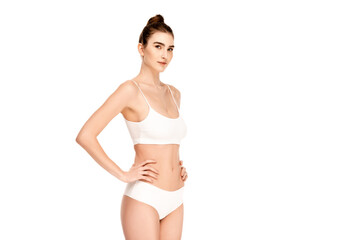 Fototapeta premium young woman in top and panties standing with hand on hip and looking at camera isolated on white