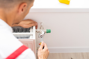A man saws off a pipe with a circular saw, flying sparks, replacement of the radiator in the apartment, plumbing work