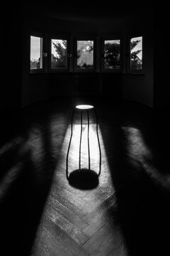 Small stool in an empty room in early morning light, black and white
