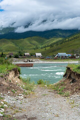 Rough mountain river against the background of a village and forest, Altai Siberia