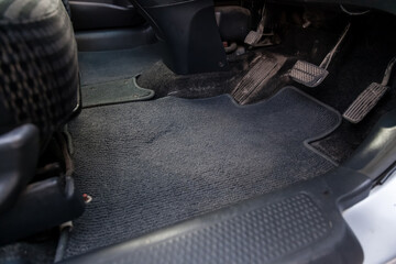 Dirty car rug made of dark blue fabric material with gas, brake and clutch pedals in a auto service...