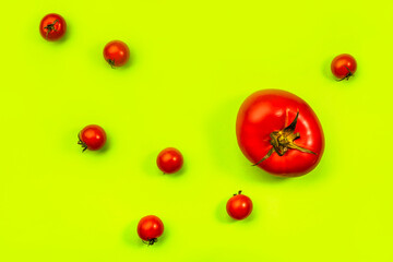 Big and cherry red tomatoes on neon green background, top view