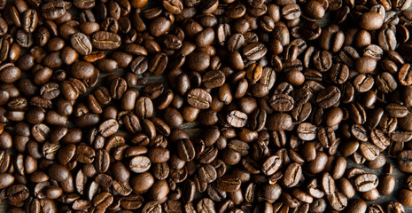 Roasted arabica coffee beans scattered on a wooden table. Fresh coffee beans.