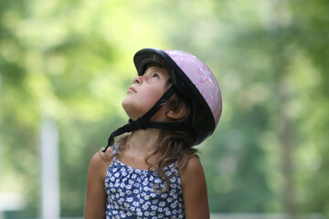 child in a pink helmet is watching something above