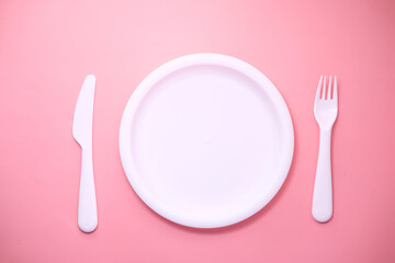 cutlery and empty plate on pink background top down