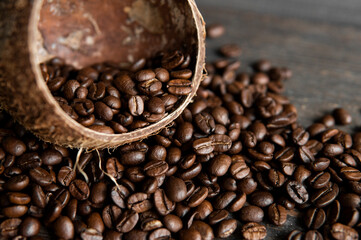 Roasted arabica coffee beans scattered on a wooden table from a coconut. Fresh coffee beans.