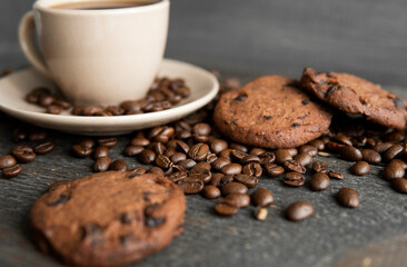 Coffee cup with cookies on wooden table background. Mug of black coffee with scattered coffee beans and cookies on a wooden table. Fresh coffee beans.