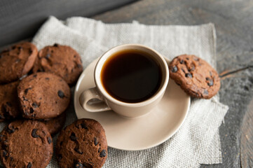 Coffee cup with cookies on wooden table background. Mug of black coffee with chocolate cookies. Fresh coffee beans.