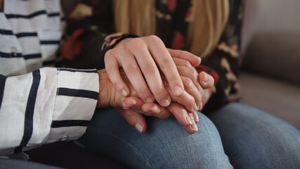 A daughter holding hands of her elderly mother. Care and support concept. High quality 4k footage