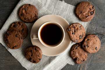 Coffee cup with cookies on wooden table background. Mug of black coffee with chocolate cookies. Fresh coffee beans.