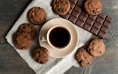 Coffee cup with cookies and chocolate on wooden table background. Mug of black coffee with chocolate cookies. Fresh coffee beans.
