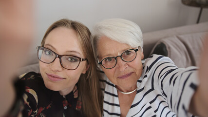 Mother and daughter taking a selfie ar having a video call. Real people. High quality photo