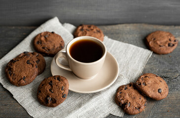 Coffee cup with cookies and chocolate on wooden table background. Mug of black coffee with chocolate cookies. Fresh coffee beans.