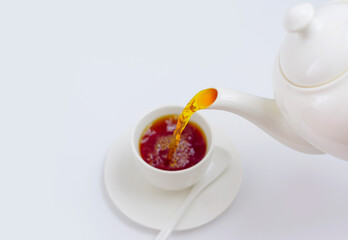 tea is poured into a white Cup from a white teapot on a white background