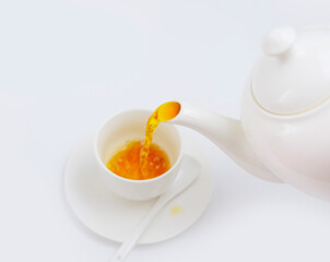 tea is poured into a white Cup from a white teapot on a white background