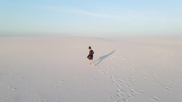 Woman in lace black dress runs in desert.