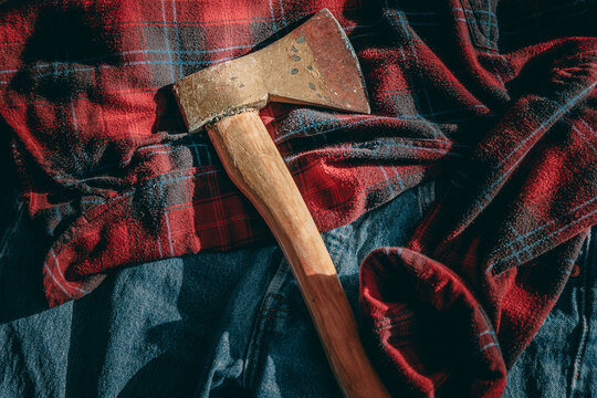 an old ax lies on a checkered red shirt and blue jeans. lumberjack equipment, Norwegian, Canadian