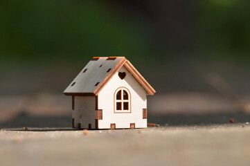 Obraz na płótnie Canvas A wooden toy house in close-up, with a blurry background, stands on a wooden table. The concept of selling, buying, renting real estate, family home, home for children, insurance, love in the house, p