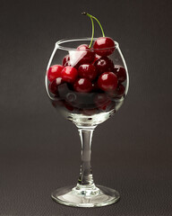 Fresh cherries in a glass goblet on a black background