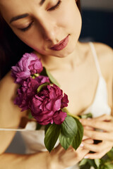 Holding flowers. Young woman resting and spending weekend at home alone at home