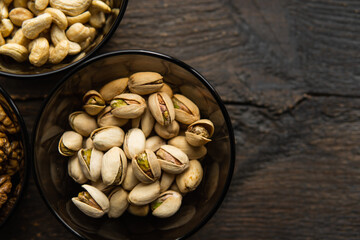 Walnut, pistachio and cashew in a small plates which standing on a black table. Nuts is a healthy vegetarian protein and nutritious food.